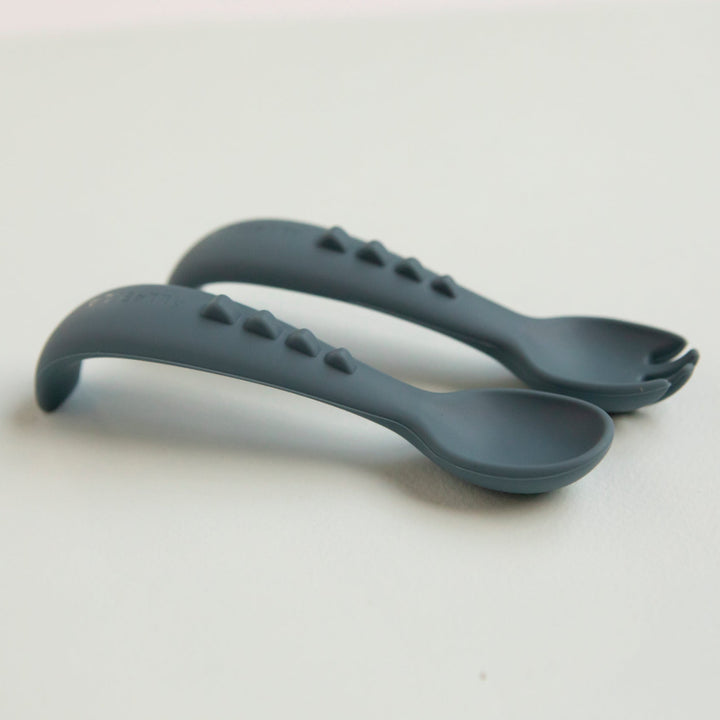 One silicone spoon and one silicone fork on a light gray background